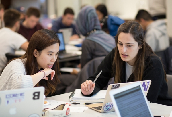 two students talking at table